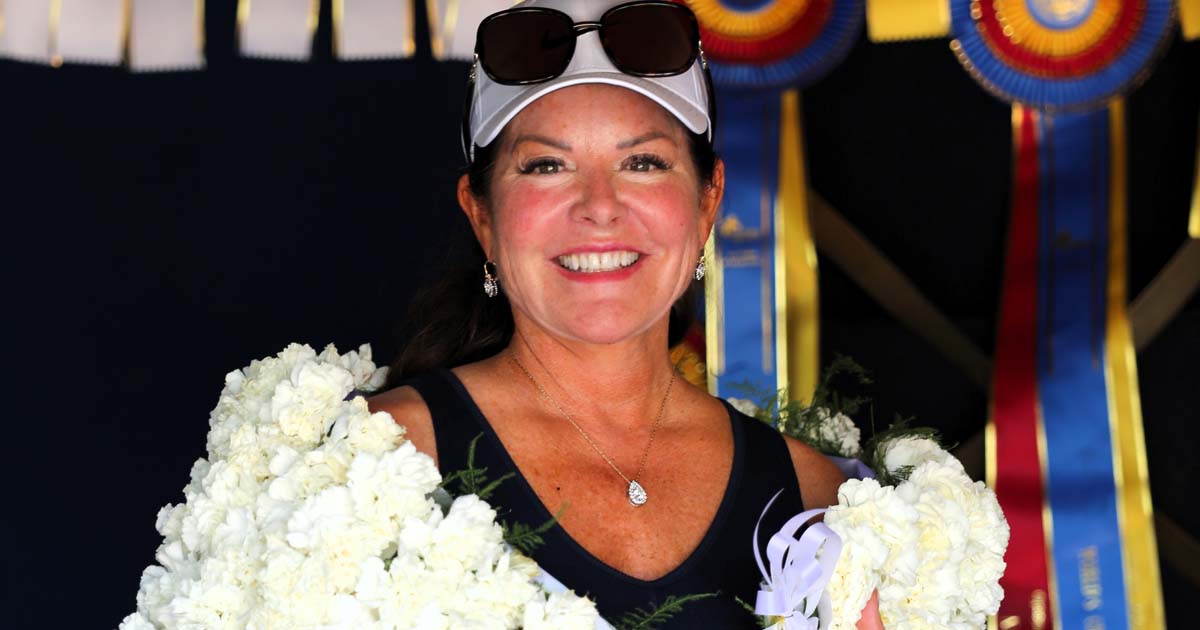 Sandy Gallagher posing with flowers around her neck after winning an equestrian competition.